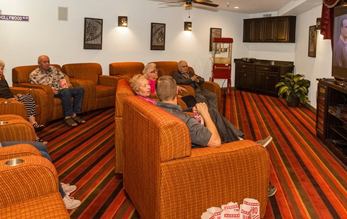 A group of people, including a man and a woman, are sitting on a couch and watching TV. They are holding a bag of popcorn. AI generated content