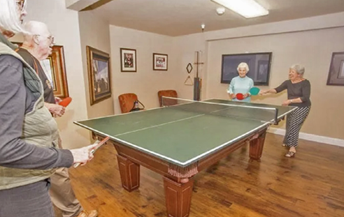 Four people are playing a game of ping pong in a room. AI generated content